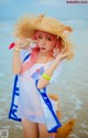 A woman in a straw hat is posing on the beach.