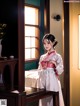 A woman in a white dress standing in front of a window.