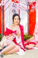 A woman in a kimono sitting on the ground next to another woman.