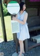 A woman in a blue and white dress standing next to a sign.