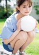 A young woman holding a white volleyball ball in her hands.