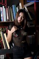 A woman standing in front of a bookshelf full of books.