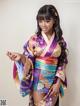 A woman in a purple and blue kimono posing for a picture.