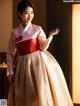 A woman in a traditional korean dress standing in front of a window.